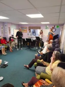 Sinfonia Viva musicians visiting 1 Oak Chilton Daycentre. A Busy room full of daycentre members and musicians playing music and having fun